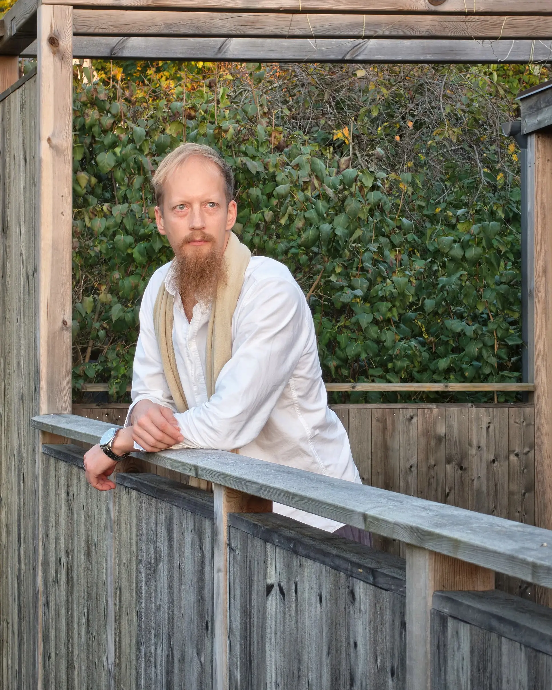 Juuso Kangas nojaa puiseen kaiteeseen pergolan alla